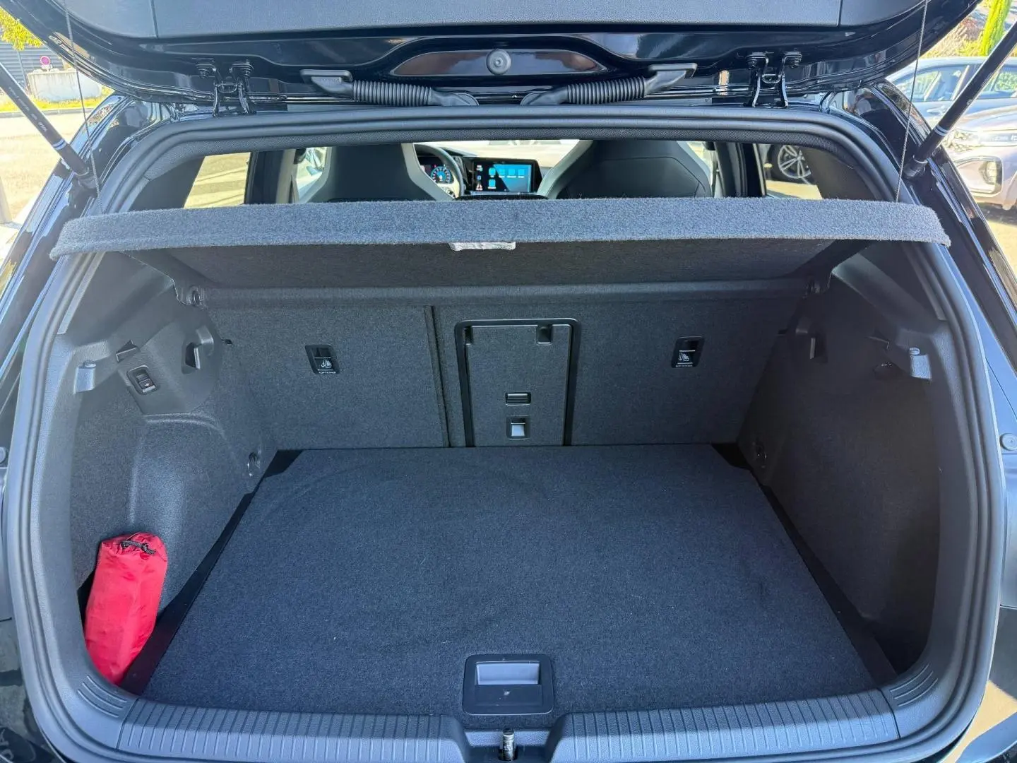 Coffre ouvert vu de l'arrière d'une Volkswagen Golf 1.5 eTSI noir Grenadilla, avec cache-bagages et intérieur gris.