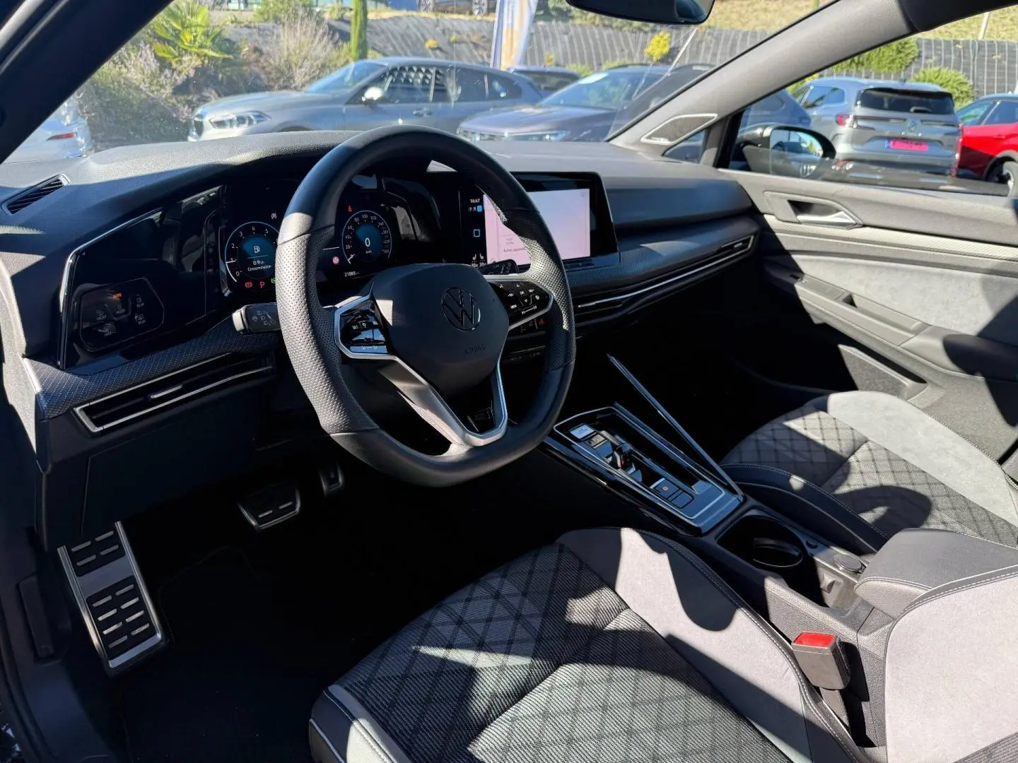 Vue intérieure côté conducteur de la Volkswagen Golf 2024, volant cuir multifonction et sièges sport en tissu gris anthracite.