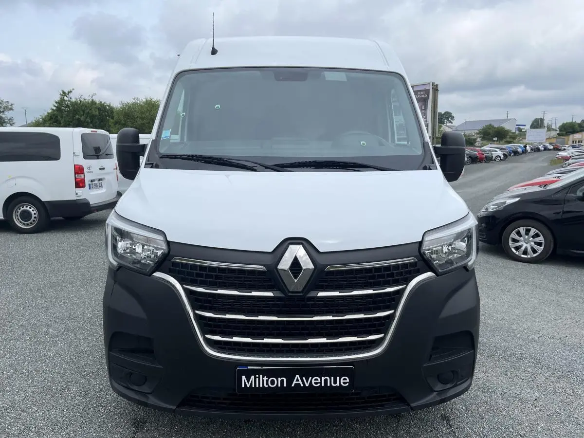 Vue de face d'un Renault Master blanc avec calandre noire et logo Renault bien visible sur un parking.