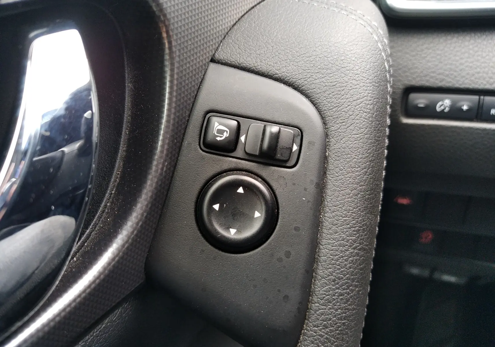 Gros plan sur les commandes de réglage des rétroviseurs côté conducteur du Nissan Qashqai blanc, intérieur noir.