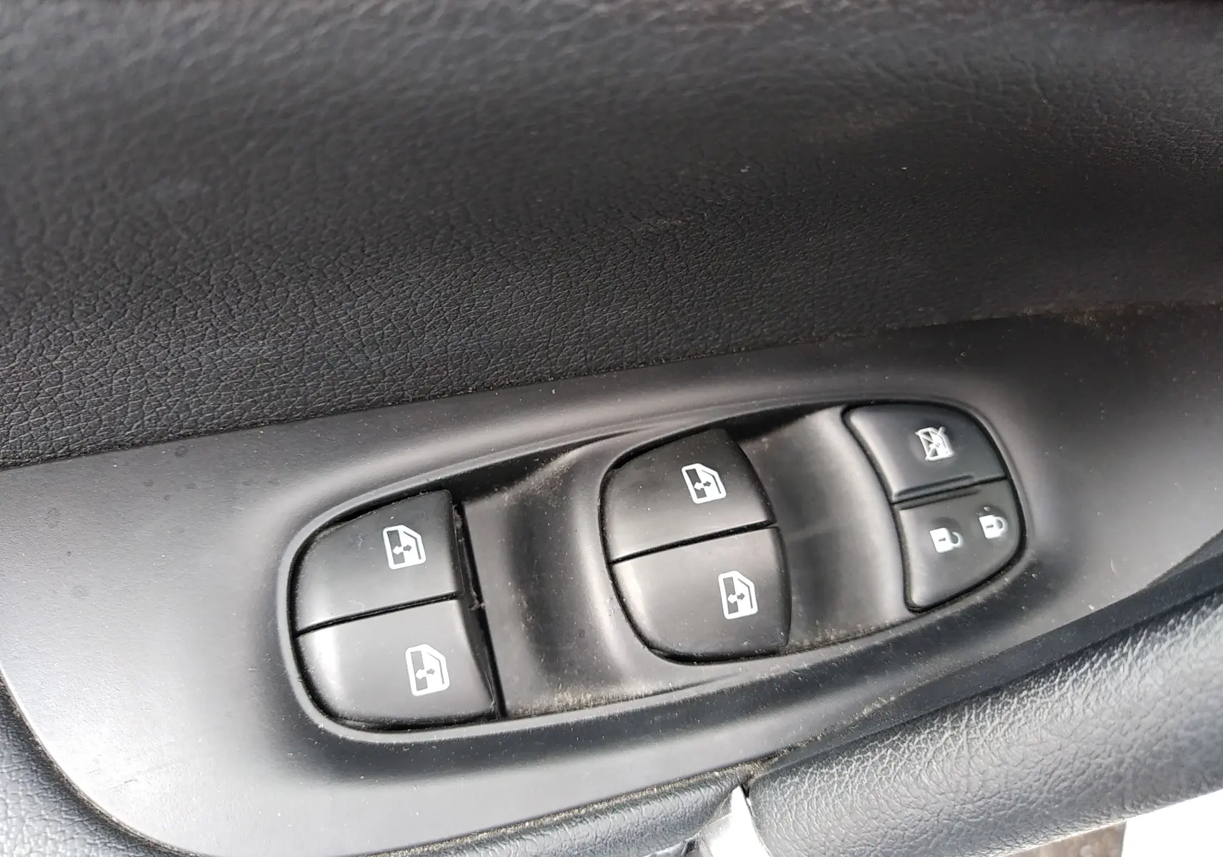 Gros plan sur les commandes de lève-vitres et verrouillage des portes côté conducteur d’un Nissan Qashqai blanc 2018.