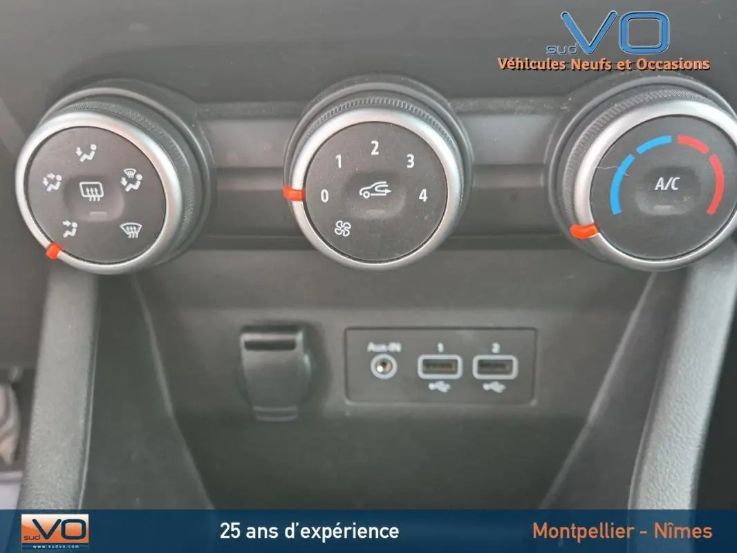 Gros plan sur les commandes de climatisation manuelle et les ports USB d'une Renault Clio V TCe 90 Equilibre noire de 2023.