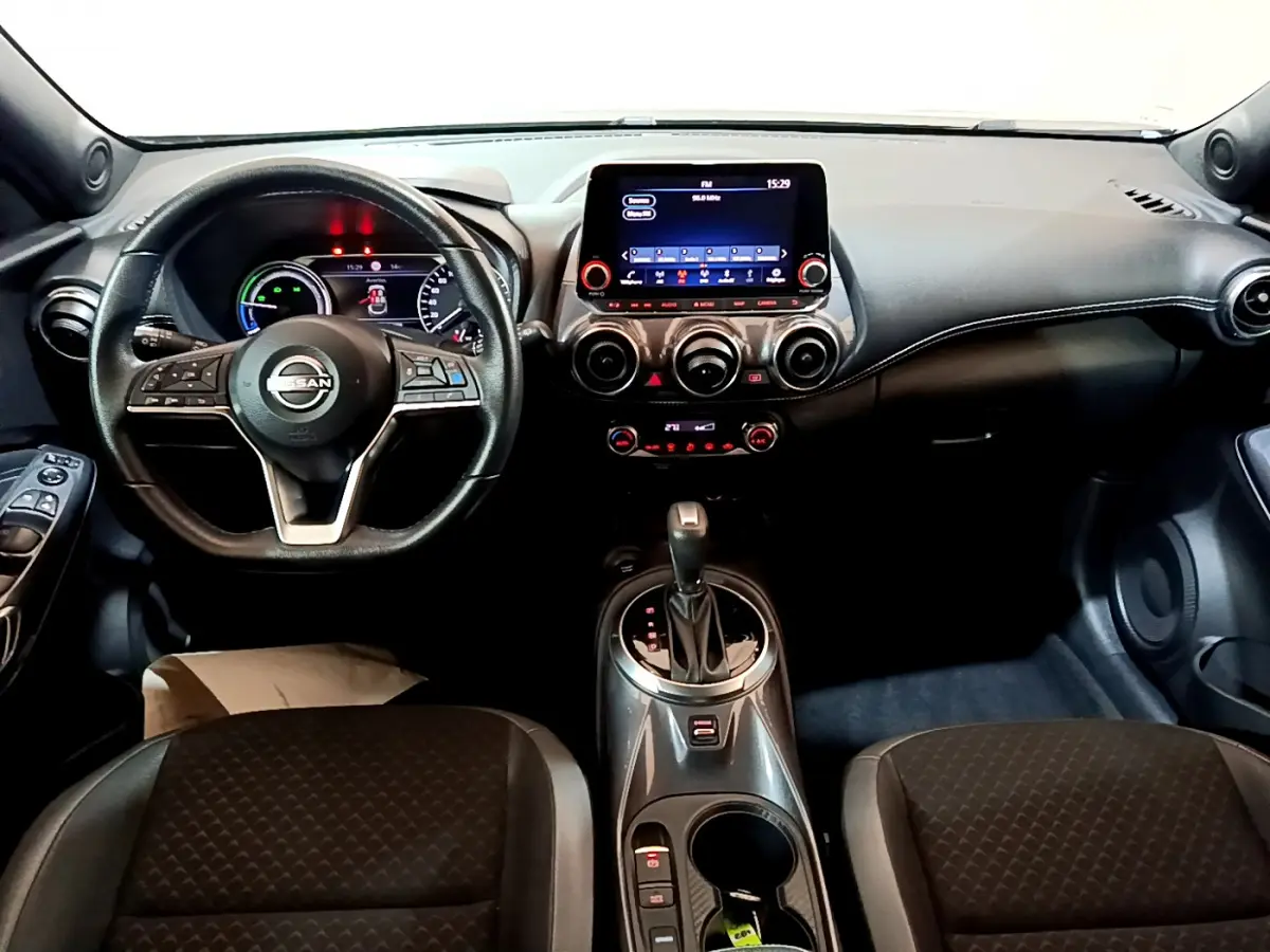 Intérieur noir du Nissan Juke Hybrid 2023 vu de face, avec volant cuir, écran tactile central et levier de boîte auto.