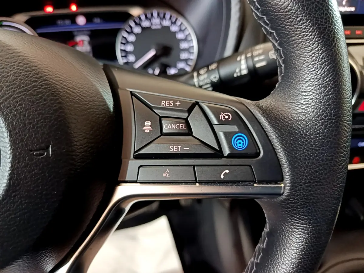 Gros plan sur le volant cuir noir du Nissan Juke Hybrid 143 Business+ 2023, avec commandes de régulateur de vitesse et appels.