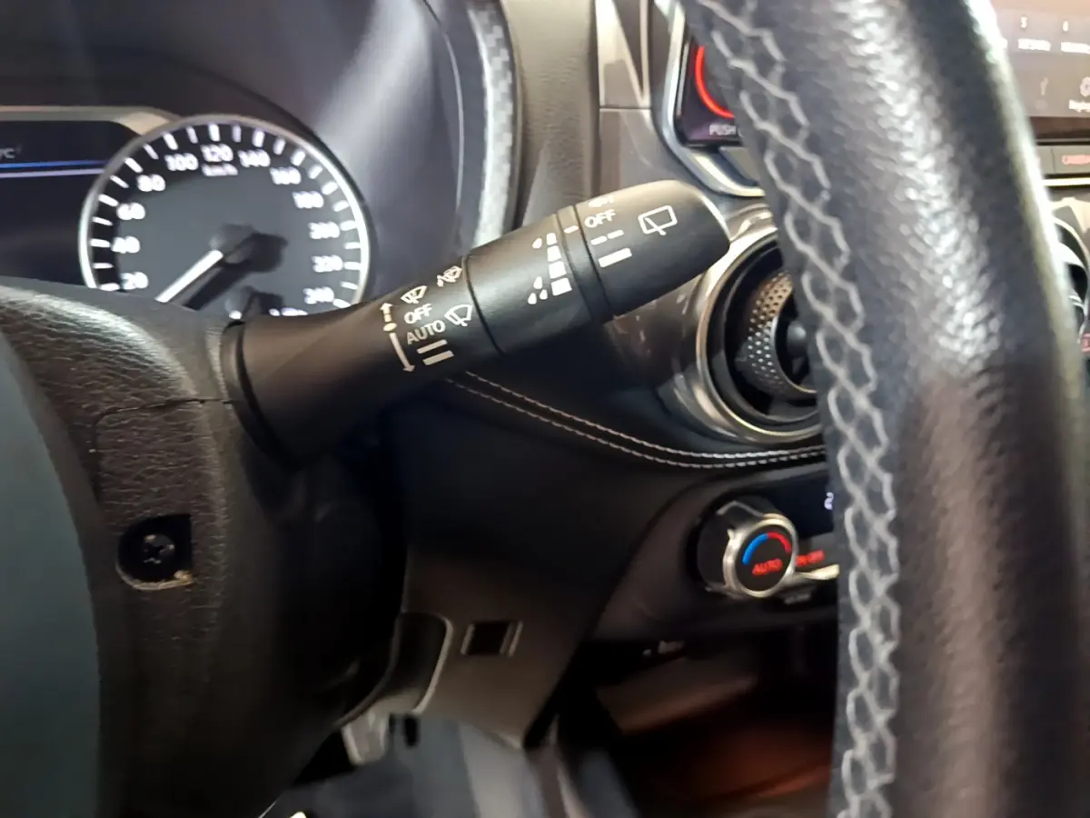 Gros plan sur la commande d'essuie-glace et le volant en cuir du Nissan Juke Hybrid 143 Business+ 2023, intérieur noir.