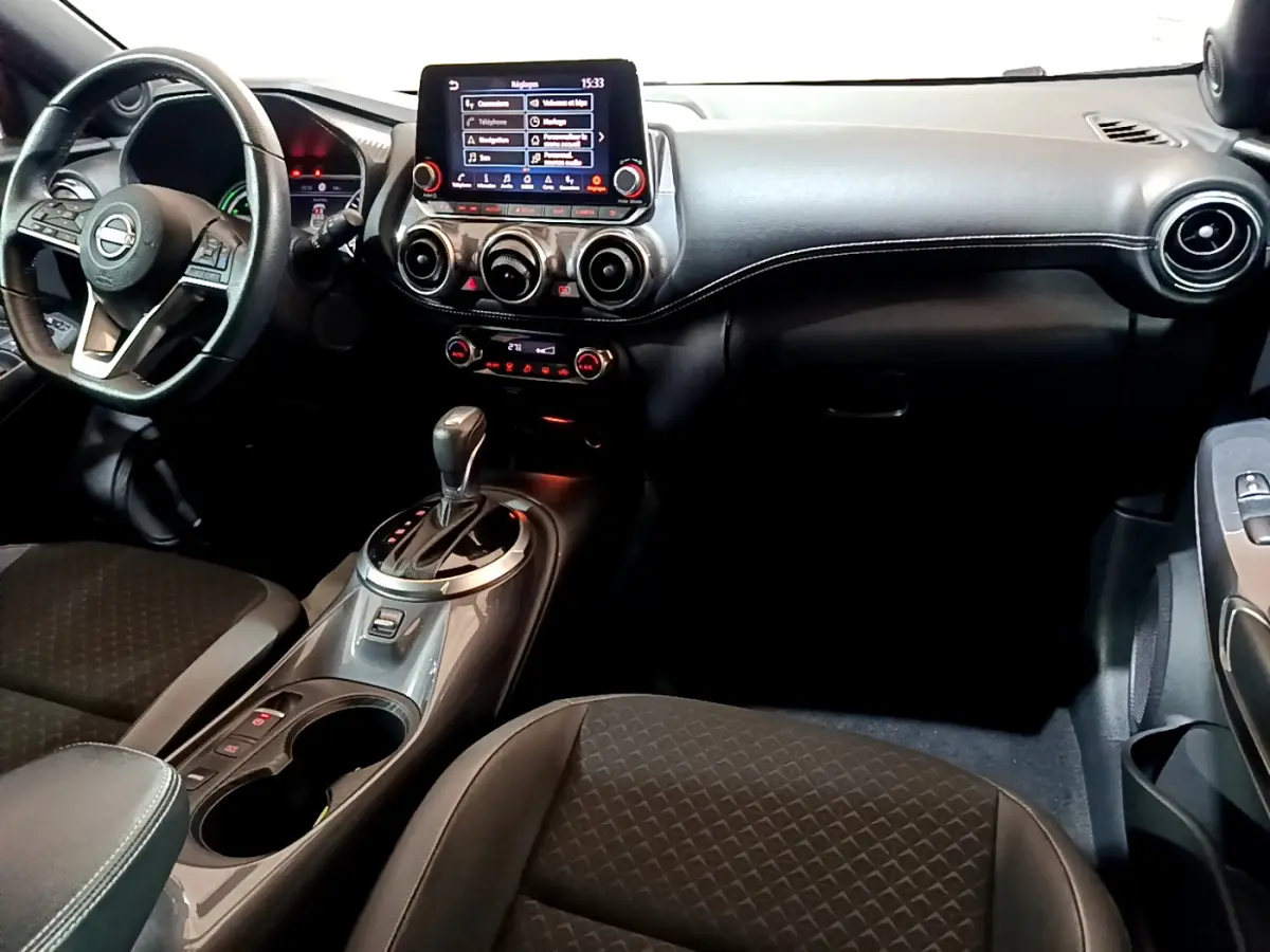 Intérieur du Nissan Juke Hybrid 143 Business+ 2023, vue côté conducteur avec tableau de bord et écran tactile central.