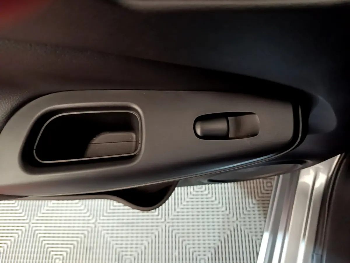 Poignée intérieure et commande de verrouillage côté gauche de la porte d’un Nissan Juke Hybrid gris foncé 2023.