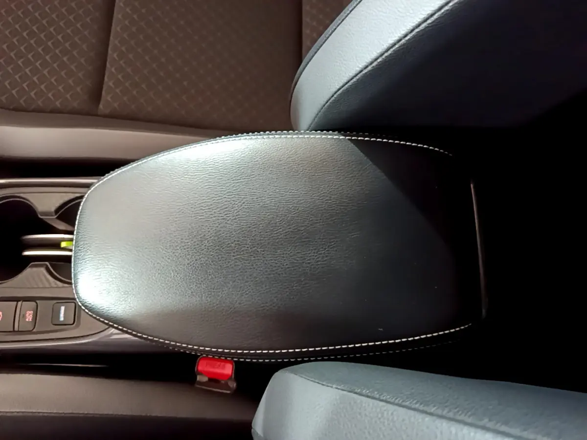 Accoudoir central en cuir noir avec surpiqûres blanches, entouré des sièges et console centrale du Nissan Juke Hybrid 2023.