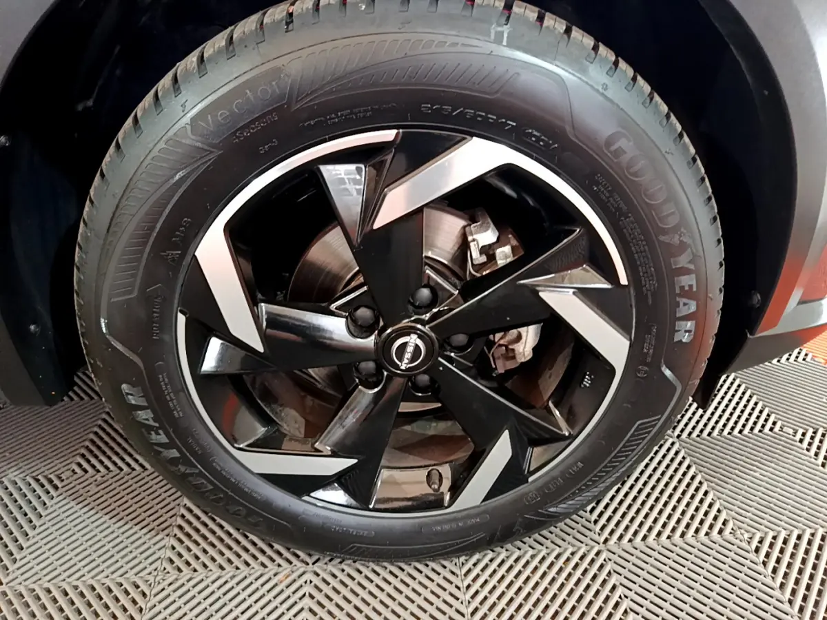 Gros plan sur la jante noire et argentée du Nissan Juke Hybrid 143 Business+ gris foncé, pneu Goodyear visible.