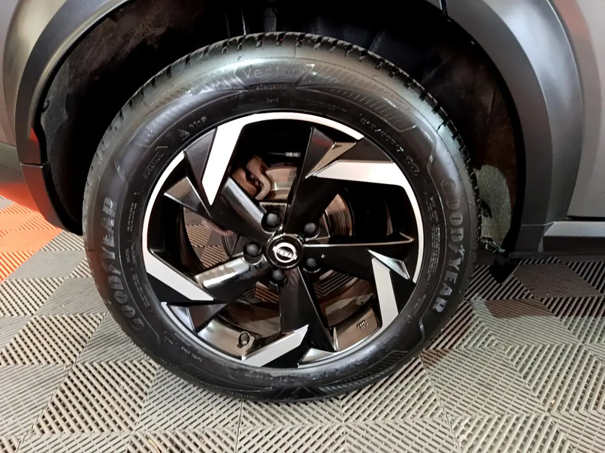 Gros plan sur la roue avant droite du Nissan Juke Hybrid 143 Business+ gris foncé avec jante noire et argentée design moderne.