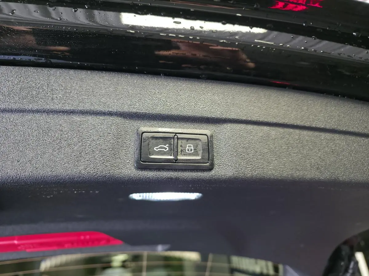 Gros plan sur les boutons d'ouverture et de verrouillage du hayon électrique d'une Audi A5 Avant noir 2025.