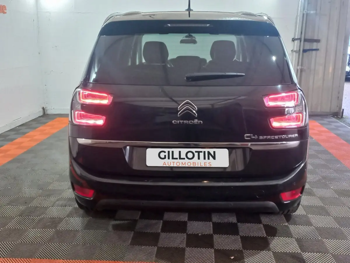 Vue arrière d'un Citroën Grand C4 Spacetourer noir avec feux arrière allumés dans un garage.