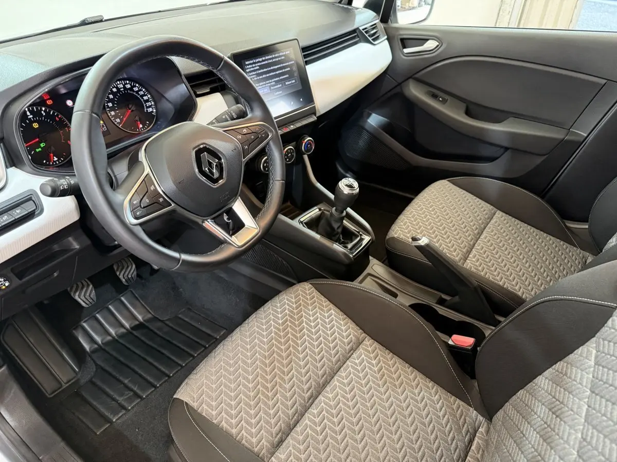 Vue intérieure côté conducteur de la Renault Clio Business TCe 100 GPL 2022, volant cuir, écran tactile et sièges gris à motifs.