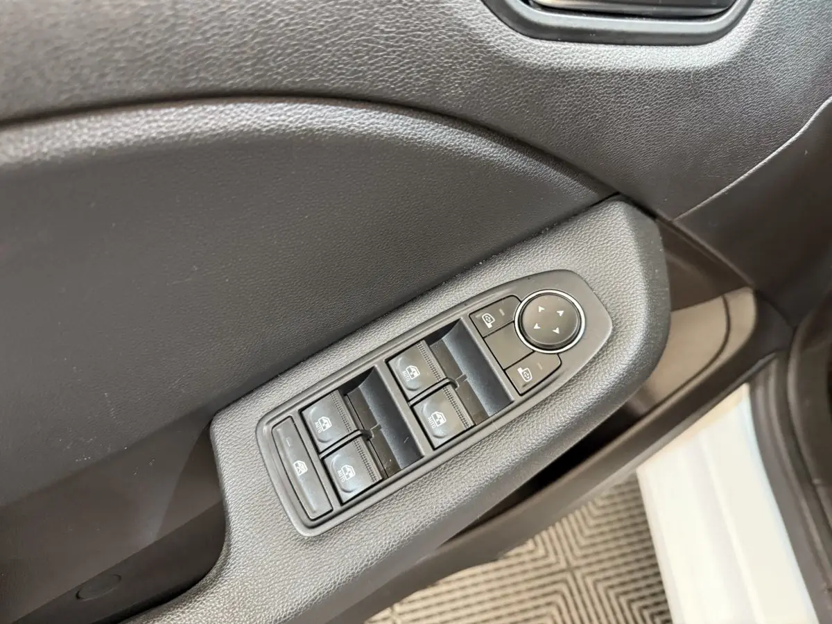Gros plan sur les commandes des vitres électriques côté conducteur d’une Renault Clio blanche, intérieur noir.