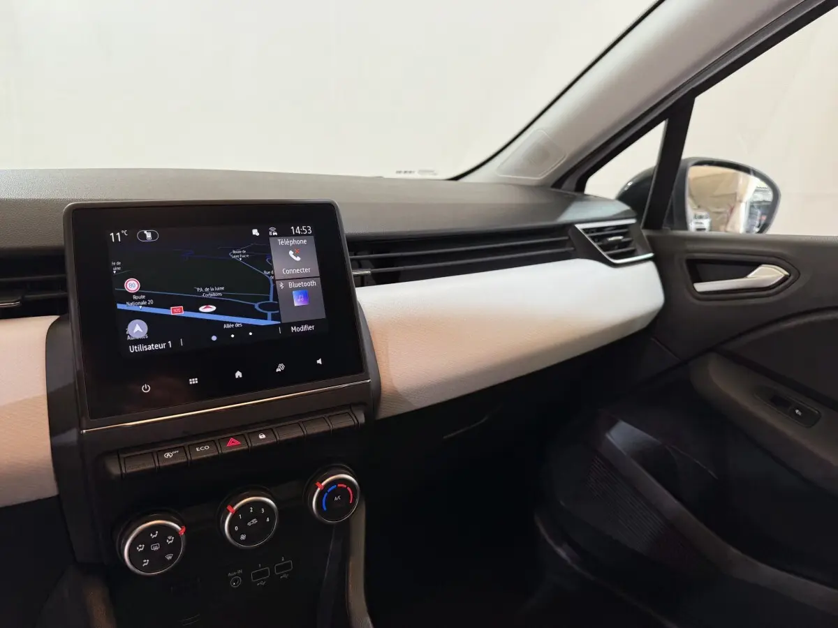 Vue intérieure côté passager de la Renault Clio Business blanche, avec écran tactile de navigation et tableau de bord clair.