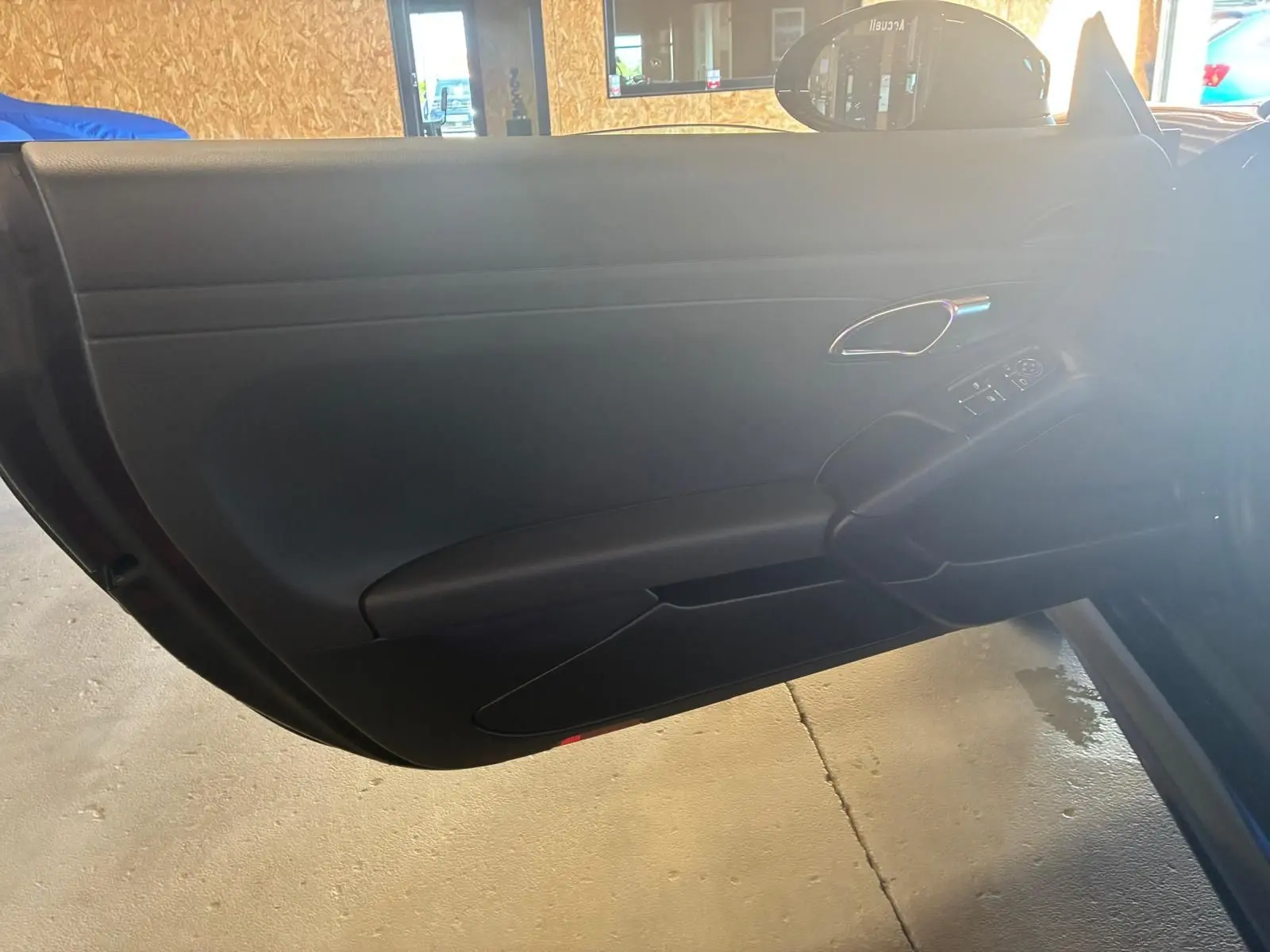 Vue rapprochée de la porte intérieure côté gauche noire d’une Porsche 718 Boxster 2018 avec poignée chromée et commandes électriques.