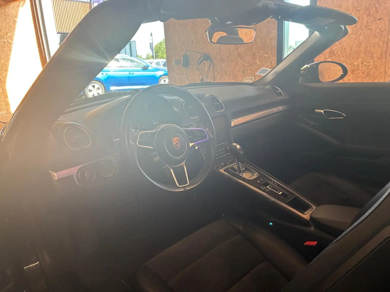Intérieur noir de la Porsche 718 Boxster 2.0 300 vue côté conducteur, mettant en valeur le volant et la console centrale.