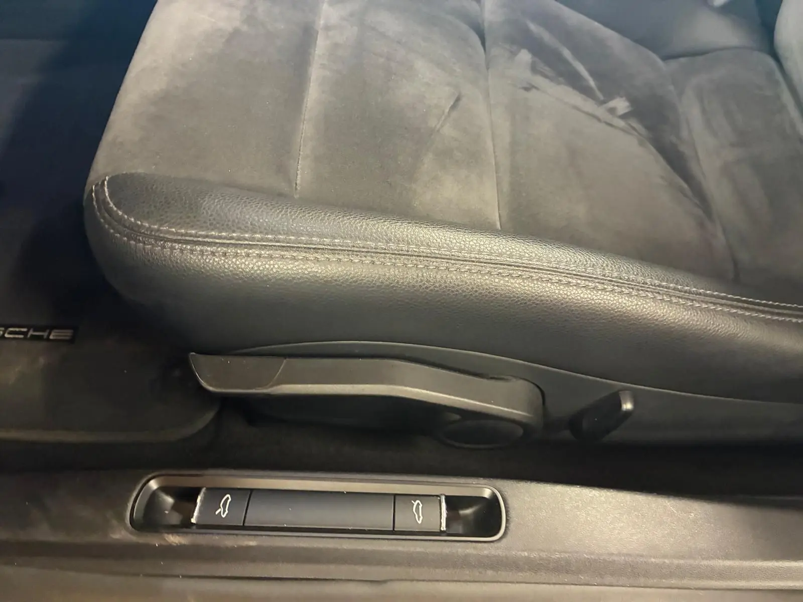 Gros plan sur le siège avant gauche en cuir noir et les commandes d'ouverture du coffre et du capot d'une Porsche 718 Boxster noire.
