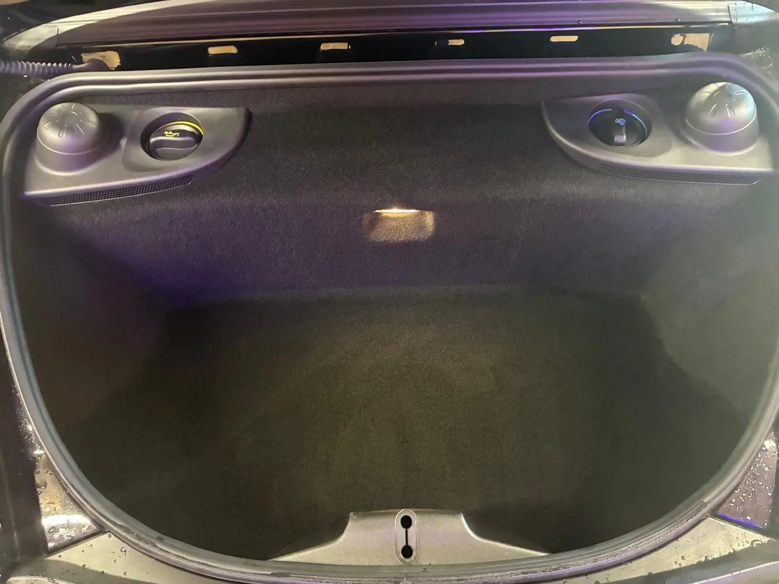 Vue plongeante sur le coffre avant noir de la Porsche 718 Boxster 2.0 300 essence, avec ouverture et compartiments latéraux visibles.