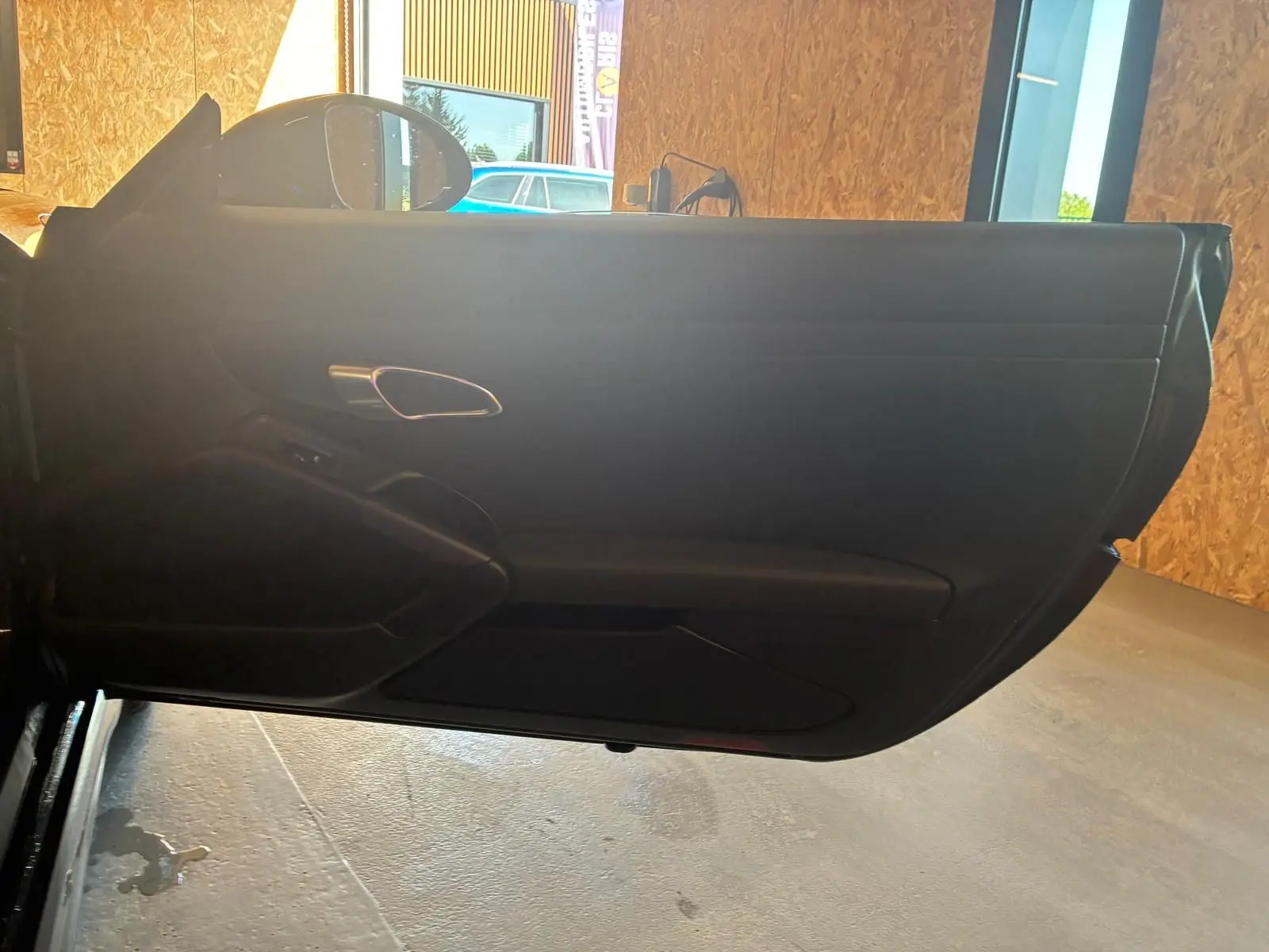 Vue intérieure de la porte côté gauche noire de la Porsche 718 Boxster 2.0 300 essence, avec poignée argentée.