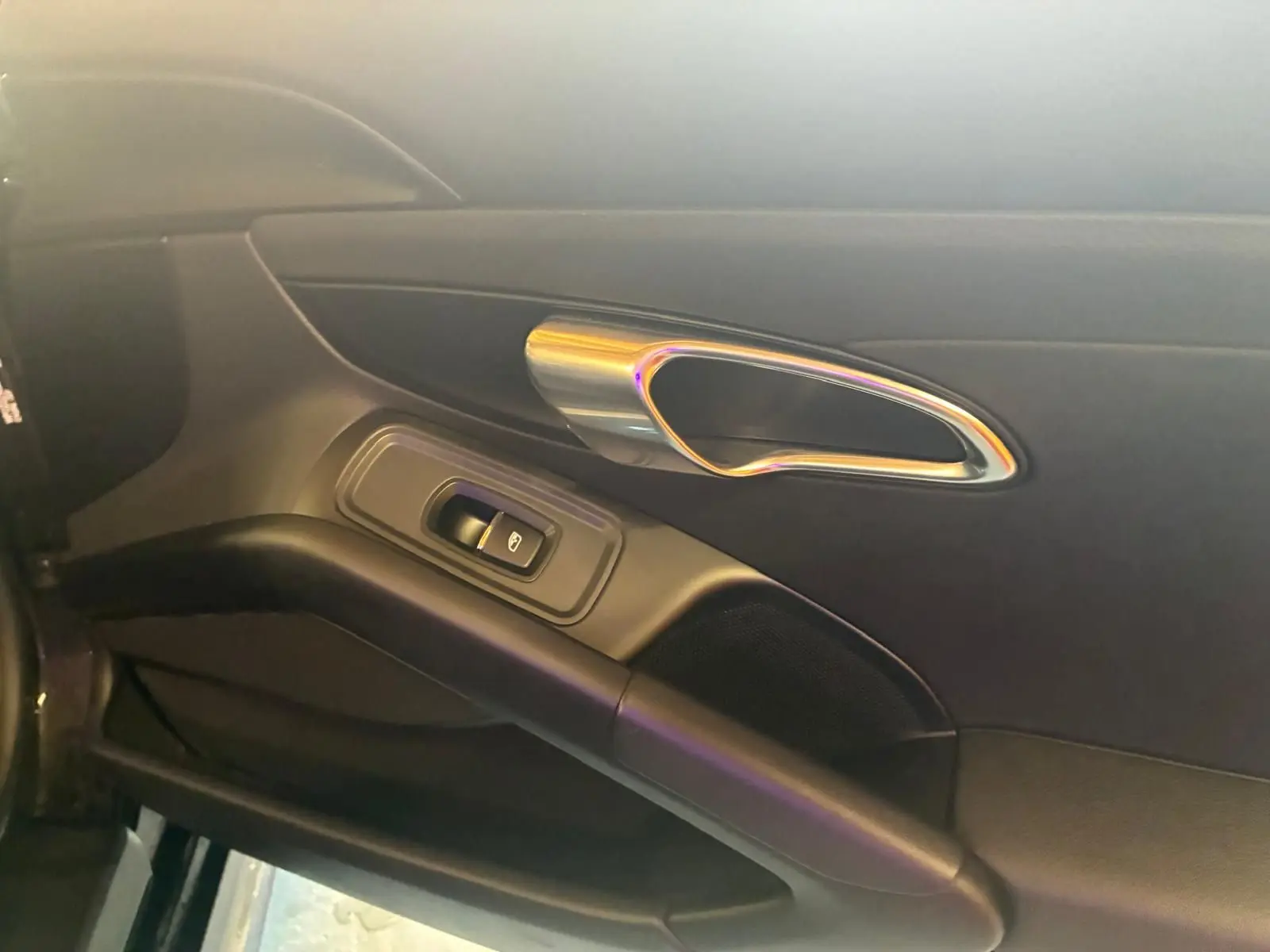 Vue rapprochée de la porte intérieure côté gauche noire du Porsche 718 Boxster 2018 avec poignée chromée et commande de vitre.