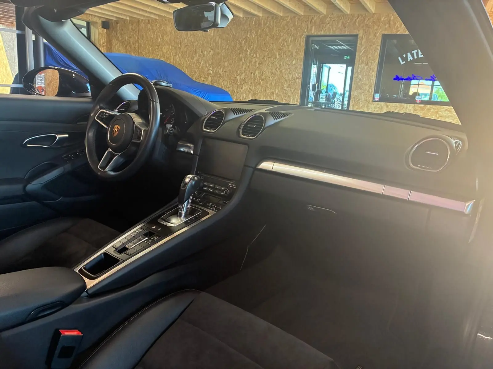 Intérieur noir de la Porsche 718 Boxster 2.0 300, vue côté conducteur, avec volant sport et console centrale automatique.