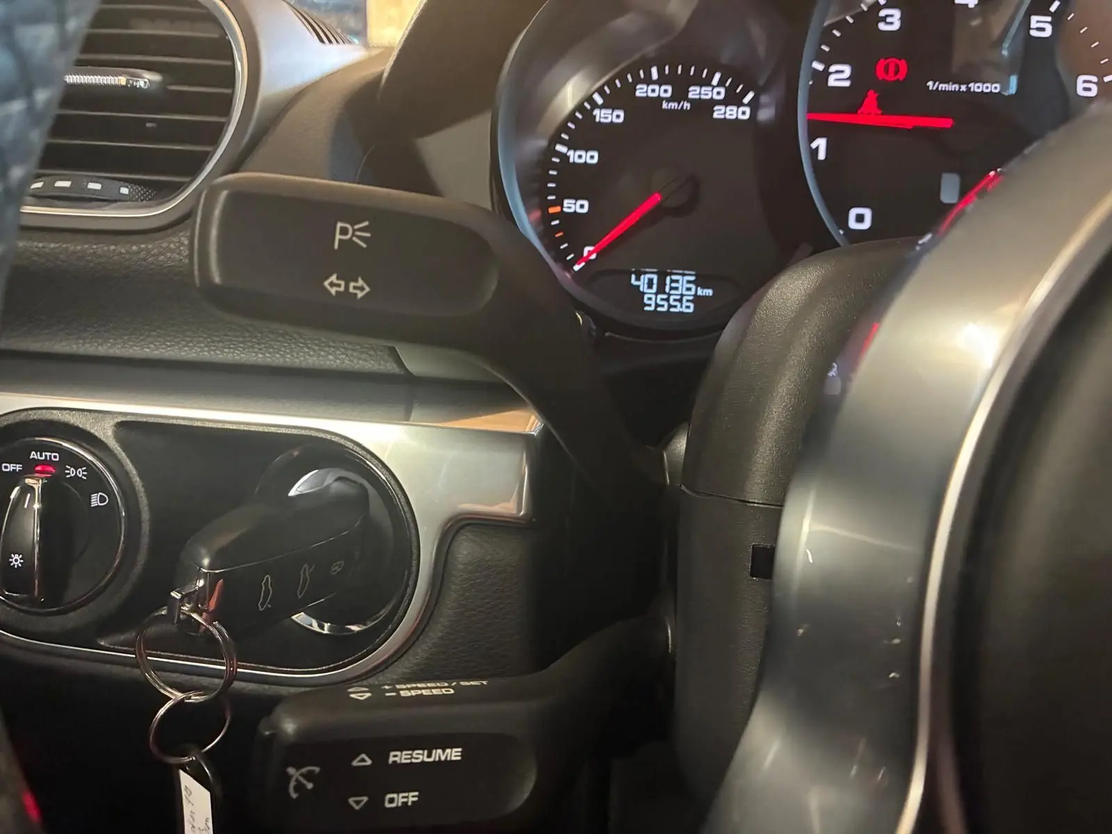 Gros plan sur le tableau de bord noir de la Porsche 718 Boxster 2.0 300, avec compteur et clé insérée.