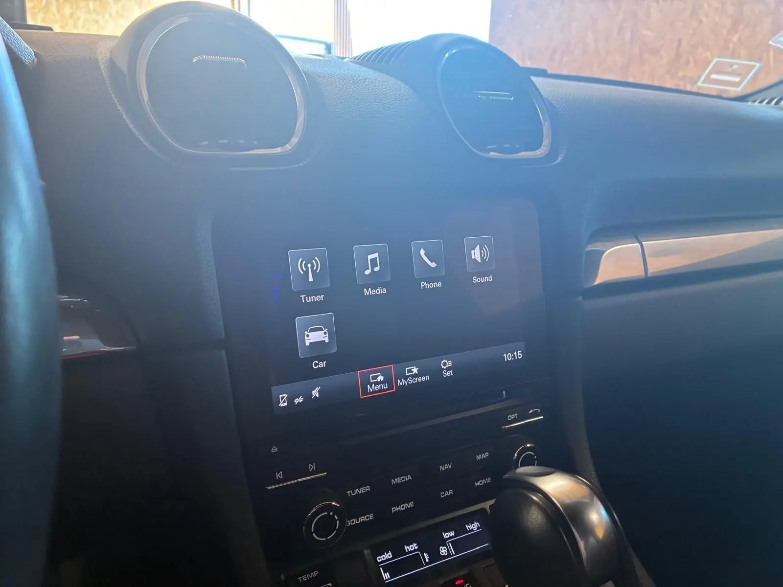 Vue intérieure centrée sur la console centrale tactile et le levier de vitesse d’une Porsche 718 Boxster noire de 2018.