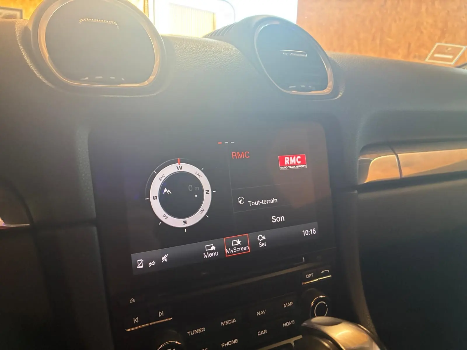 Vue rapprochée de l’écran tactile central du Porsche 718 Boxster noir, affichant la boussole et la radio RMC.