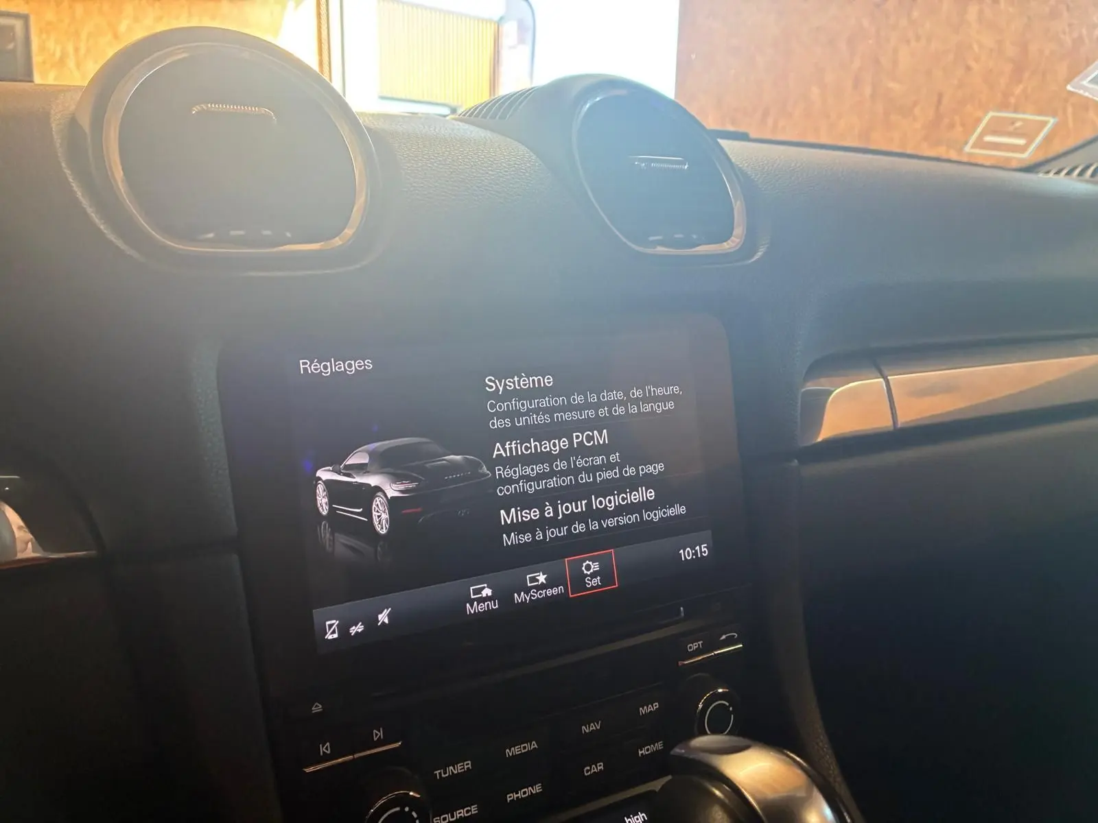 Vue intérieure du tableau de bord de la Porsche 718 Boxster noire, avec écran tactile affichant les réglages système.