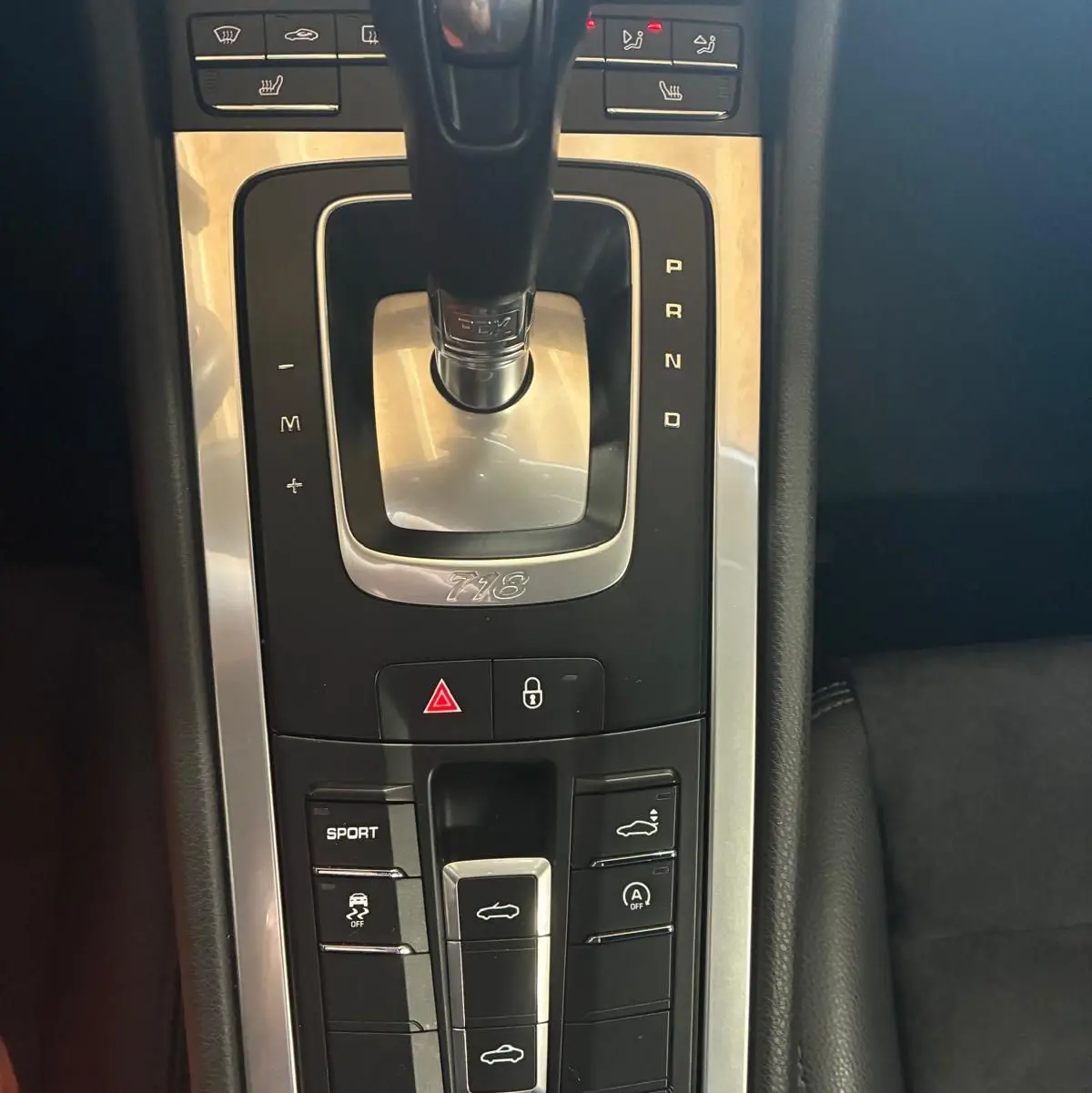 Gros plan sur la console centrale de la Porsche 718 Boxster noire, mettant en valeur le levier de vitesse automatique et les boutons de contrôle.