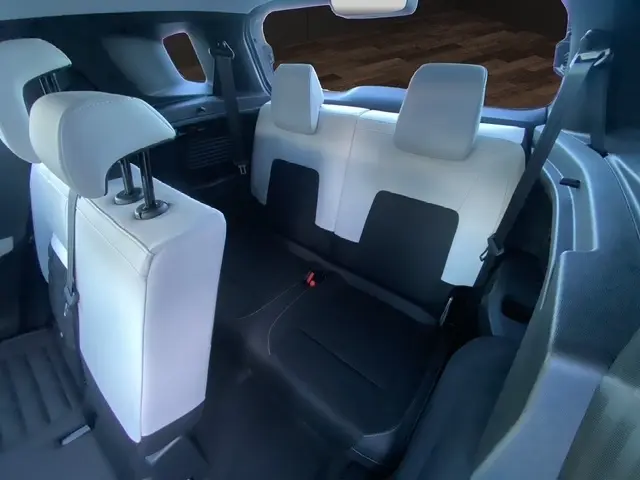 Vue intérieure arrière montrant la troisième rangée de sièges bicolores noir et blanc du Citroën C3 Aircross hybride 2026.