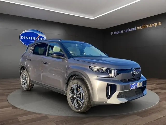 Vue 3/4 avant d'une Citroën C3 Aircross hybride gris foncé, avec jantes distinctives et toit noir en showroom.