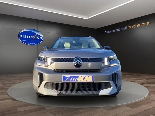 Vue frontale d'une Citroën C3 Aircross hybride gris foncé avec calandre distinctive et phares LED allumés.
