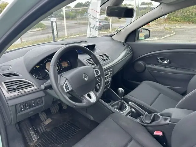 Vue intérieure côté conducteur de la Renault Mégane 3 gris 2012, avec volant multifonction et boîte manuelle.