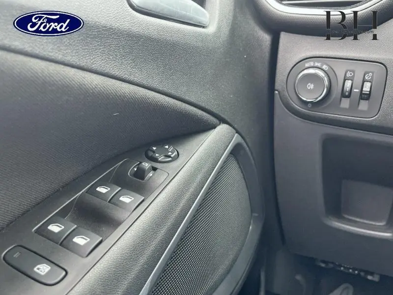 Détail intérieur du panneau de porte côté conducteur avec commandes électriques et réglages des phares, finition noire.