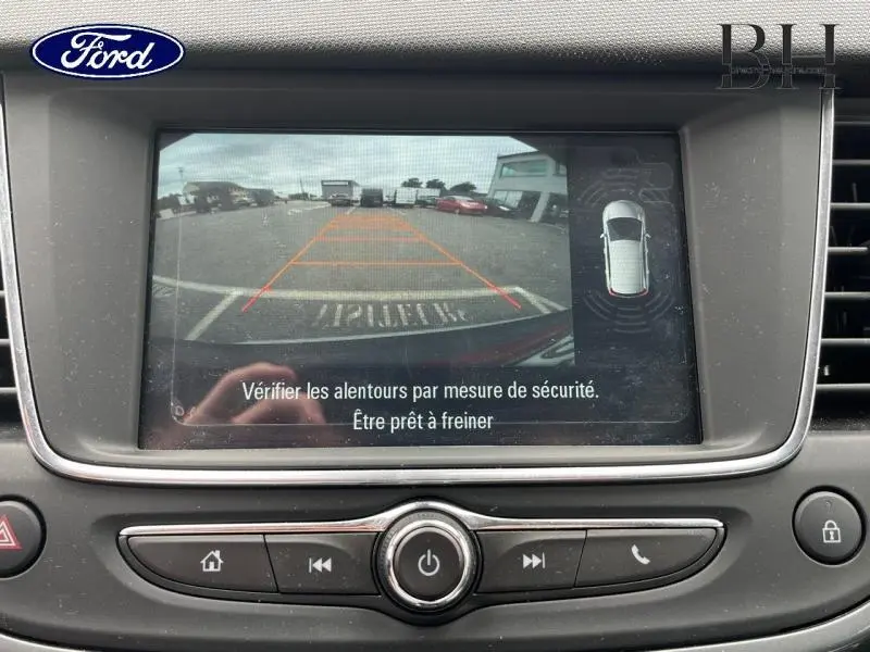Image de la caméra de recul d'un Opel Crossland rouge Kardio, vue arrière avec lignes de guidage orange.