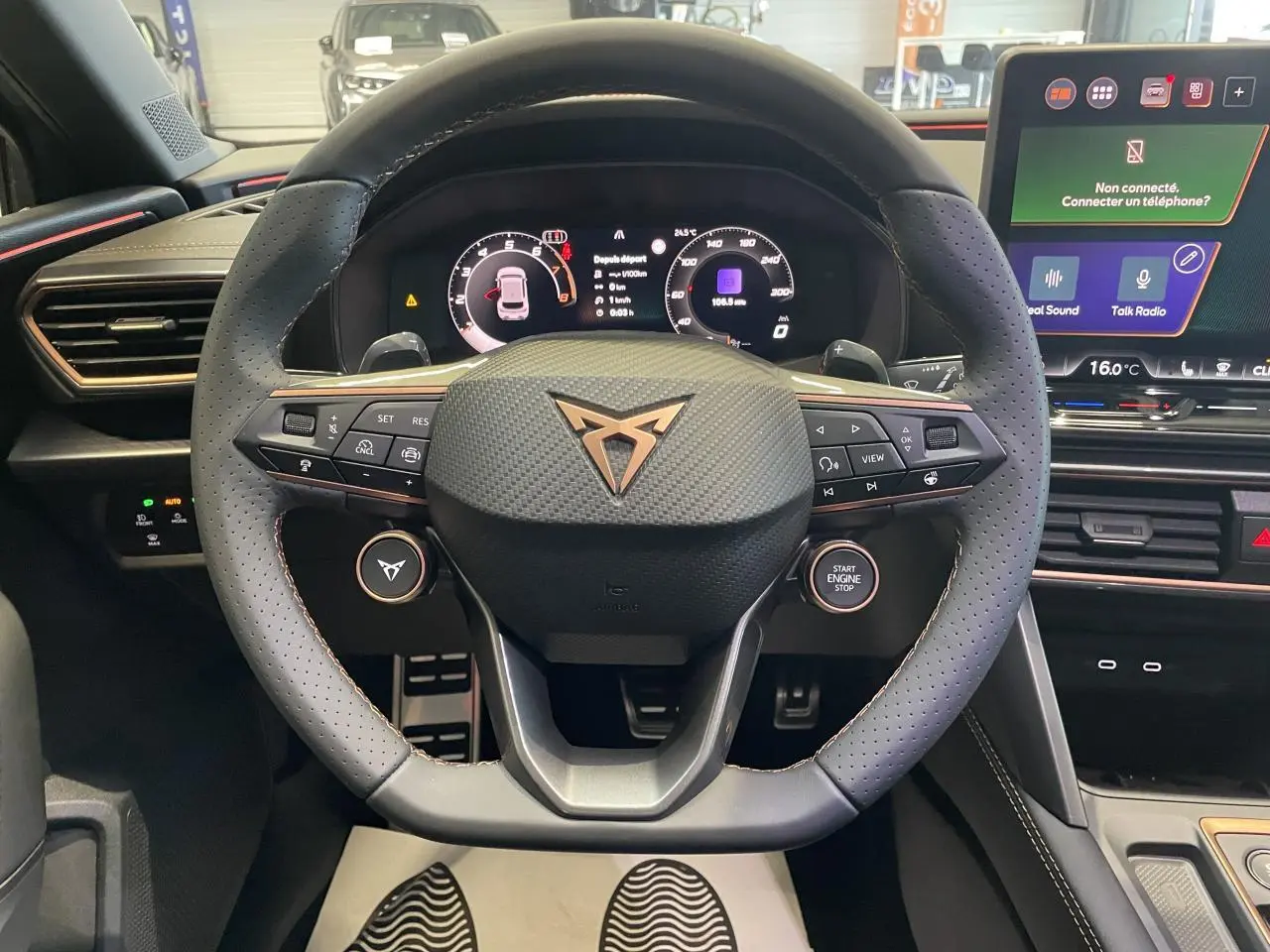 Vue centrée sur le volant perforé noir avec logo Cupra cuivré, tableau de bord digital et écran tactile HD à droite.