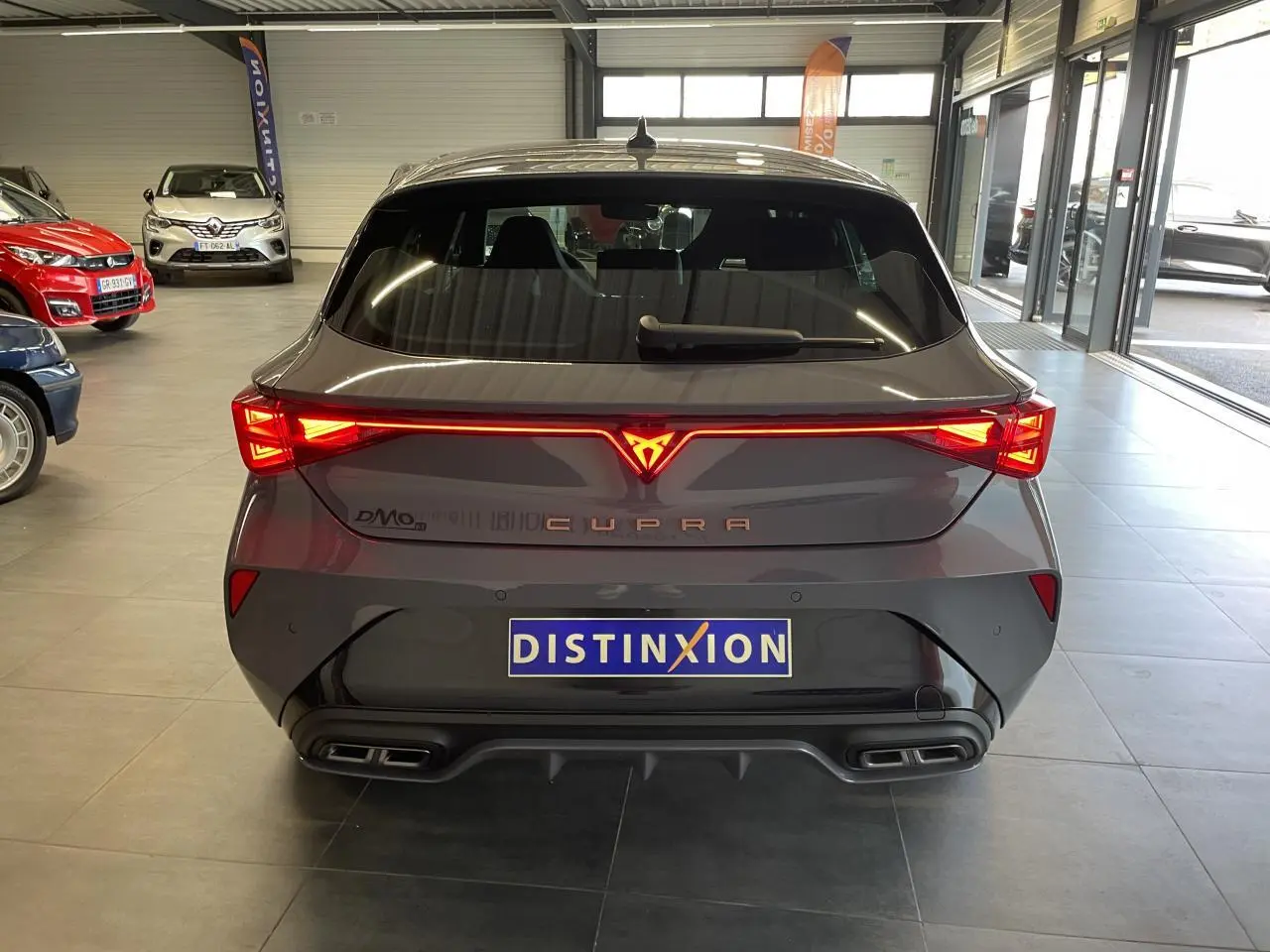 Vue arrière d'une CUPRA Leon gris Graphène avec feux arrière Tri-LED et double sortie d'échappement noire.