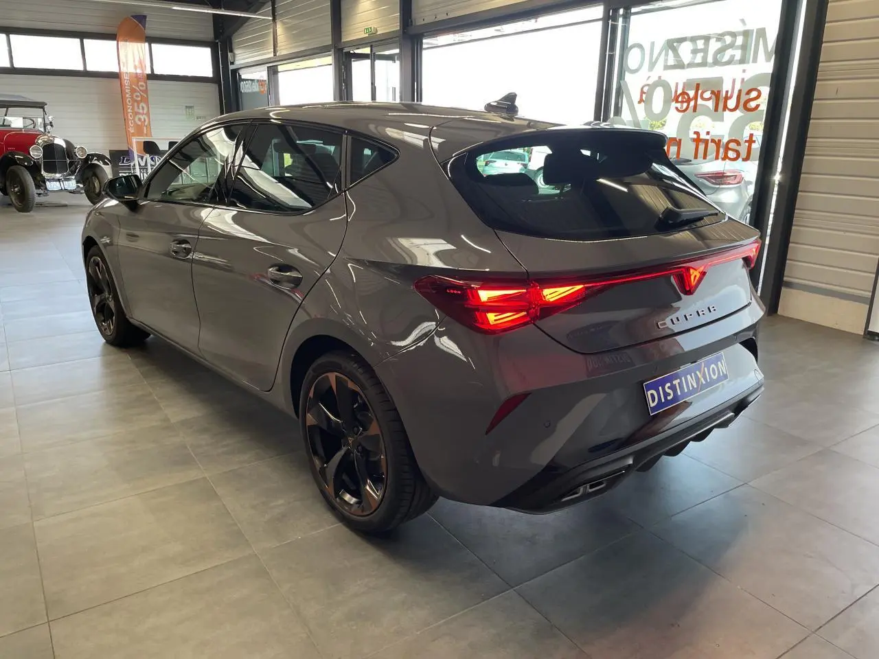 Vue 3/4 arrière droite d'une CUPRA Leon gris Graphène avec feux arrière Tri-LED et jantes alliage 18'' cuivrées.