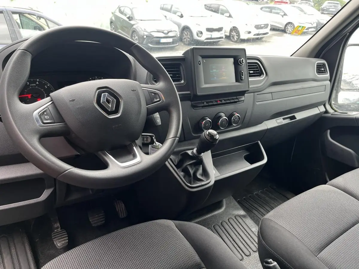 Vue intérieure côté conducteur du Renault Master 2023 avec volant, tableau de bord noir et levier de vitesses manuel.