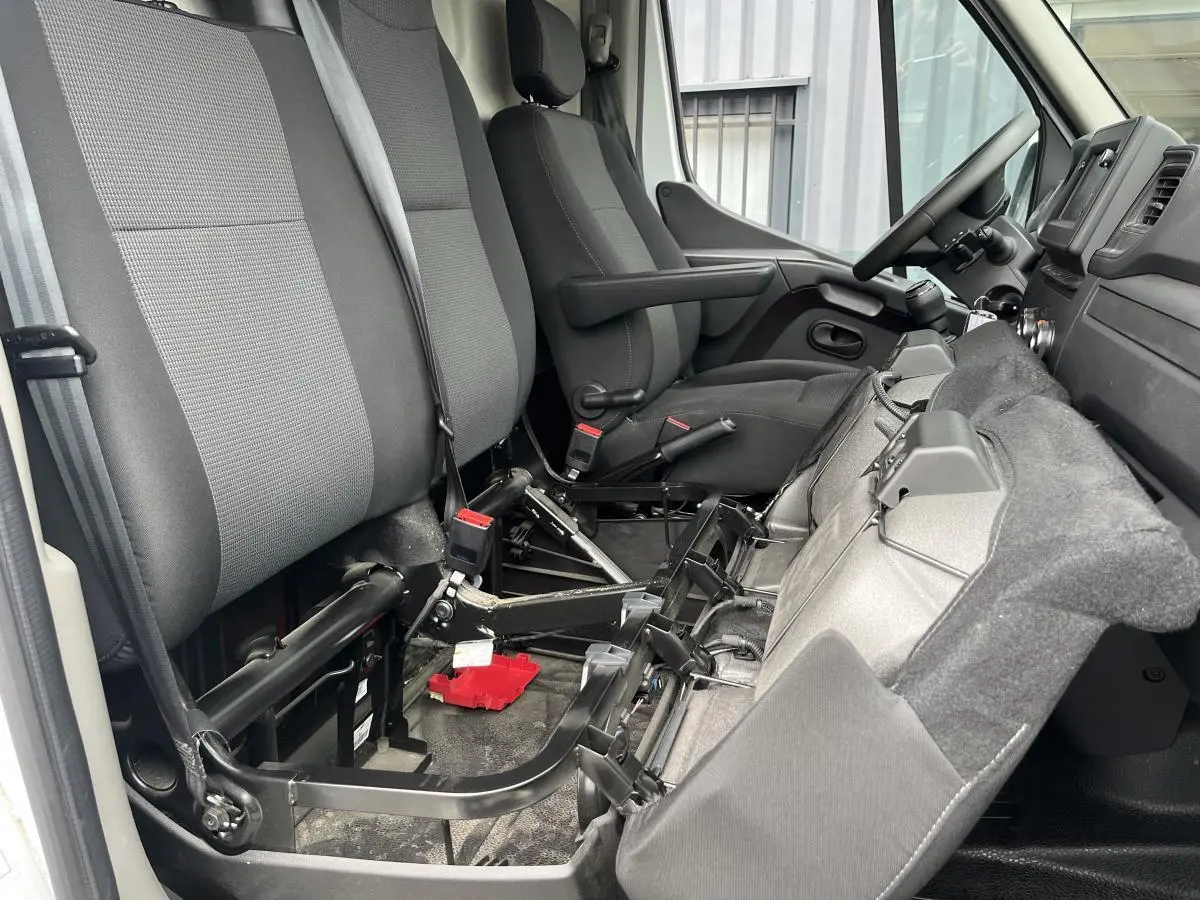 Vue intérieure côté passager du Renault Master blanc 2023, montrant la banquette rabattue et les sièges en tissu gris.