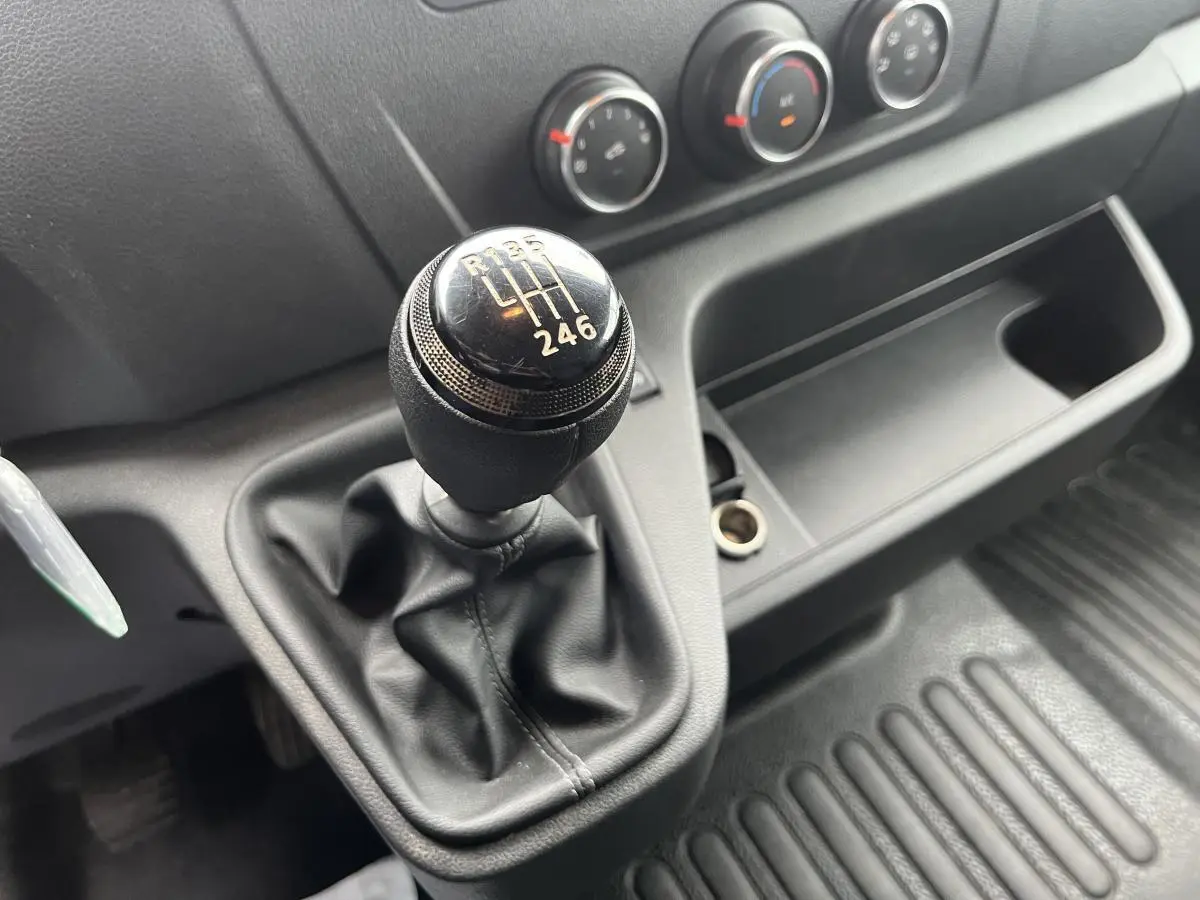 Gros plan sur le levier de vitesses manuel noir du Renault Master 2023 avec commandes de climatisation en arrière-plan.