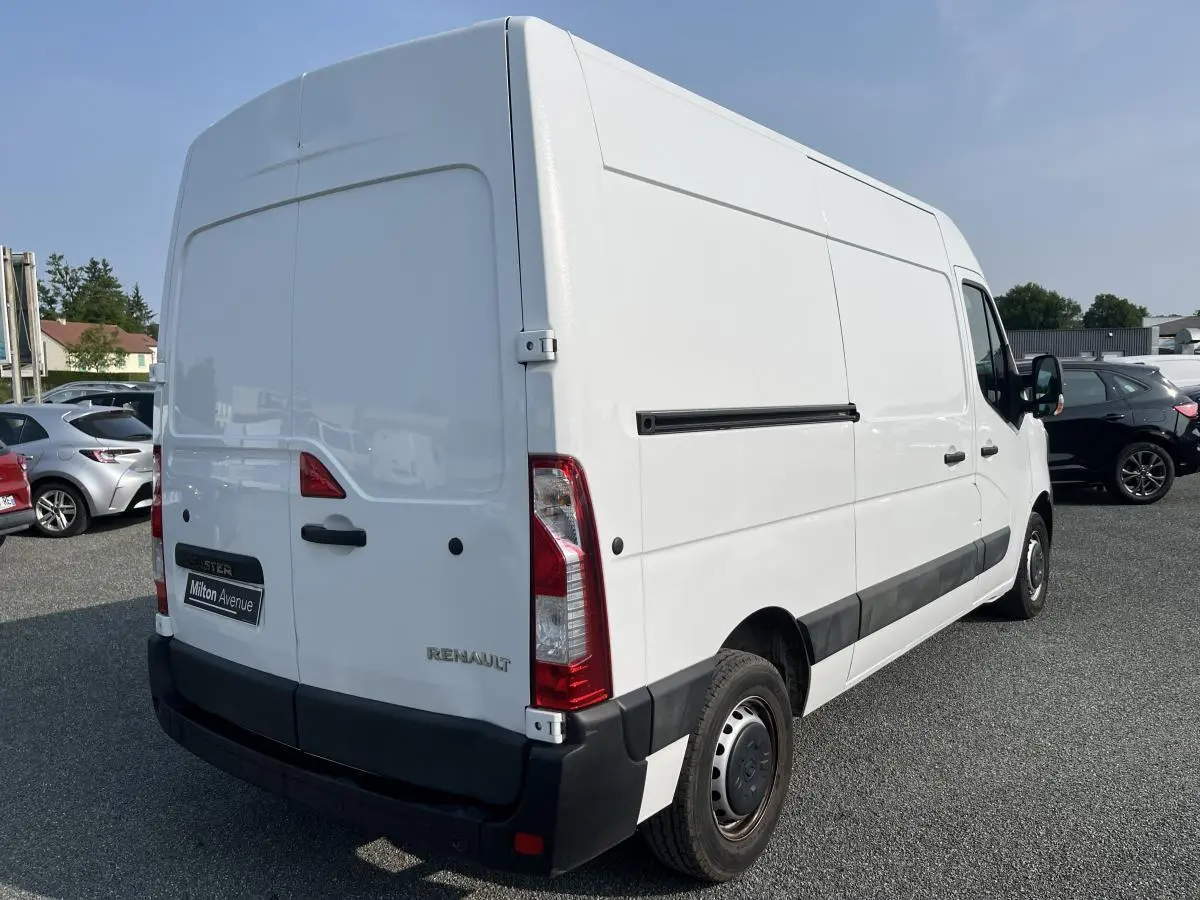 Renault Master blanc vu en 3/4 arrière droit, avec portes arrière tôlées et baguettes de protection noires.