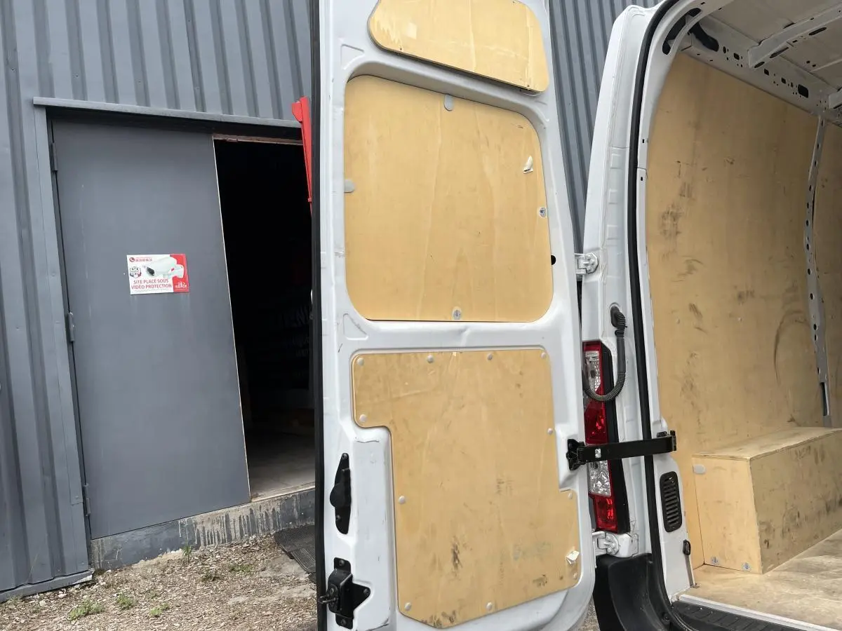 Vue arrière porte ouverte du Renault Master blanc avec habillage bois intérieur et protection latérale complète.