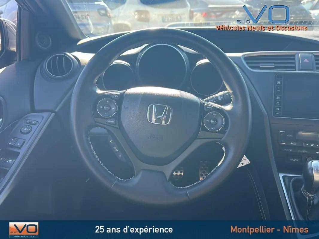 Vue intérieure centrée sur le volant multifonction d'une Honda Civic gris, avec tableau de bord et commandes visibles.
