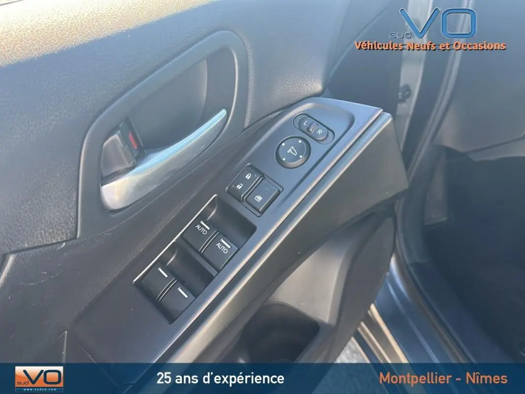 Gros plan sur la commande des vitres électriques et rétroviseurs côté conducteur d'une Honda Civic gris 2015.