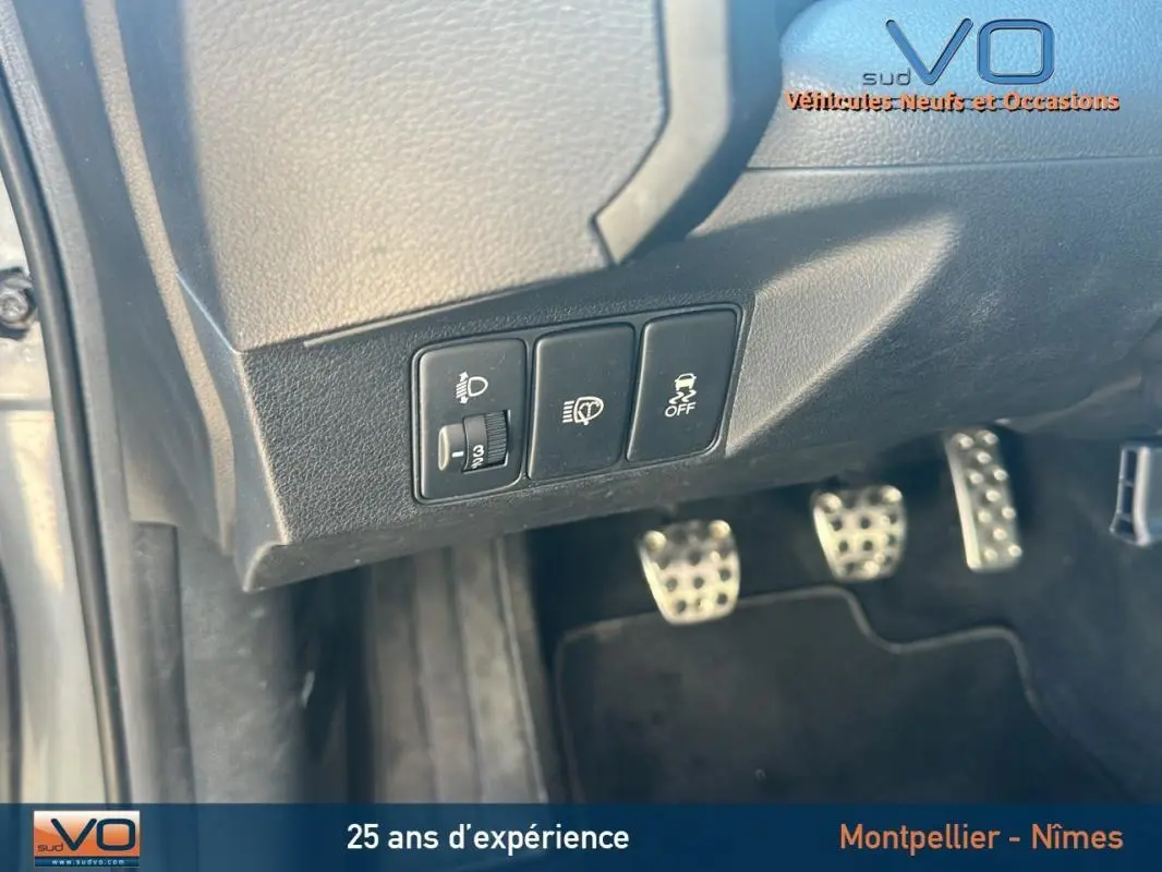 Gros plan sur les commandes sous le tableau de bord et les pédales en aluminium d'une Honda Civic gris 2015 avec boîte manuelle.