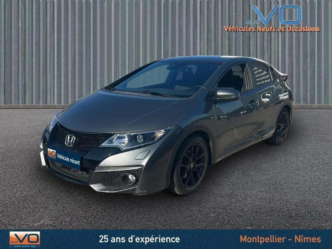 Vue 3/4 avant d'une Honda Civic gris foncé de 2015 avec jantes alliage noires et vitres surteintées.