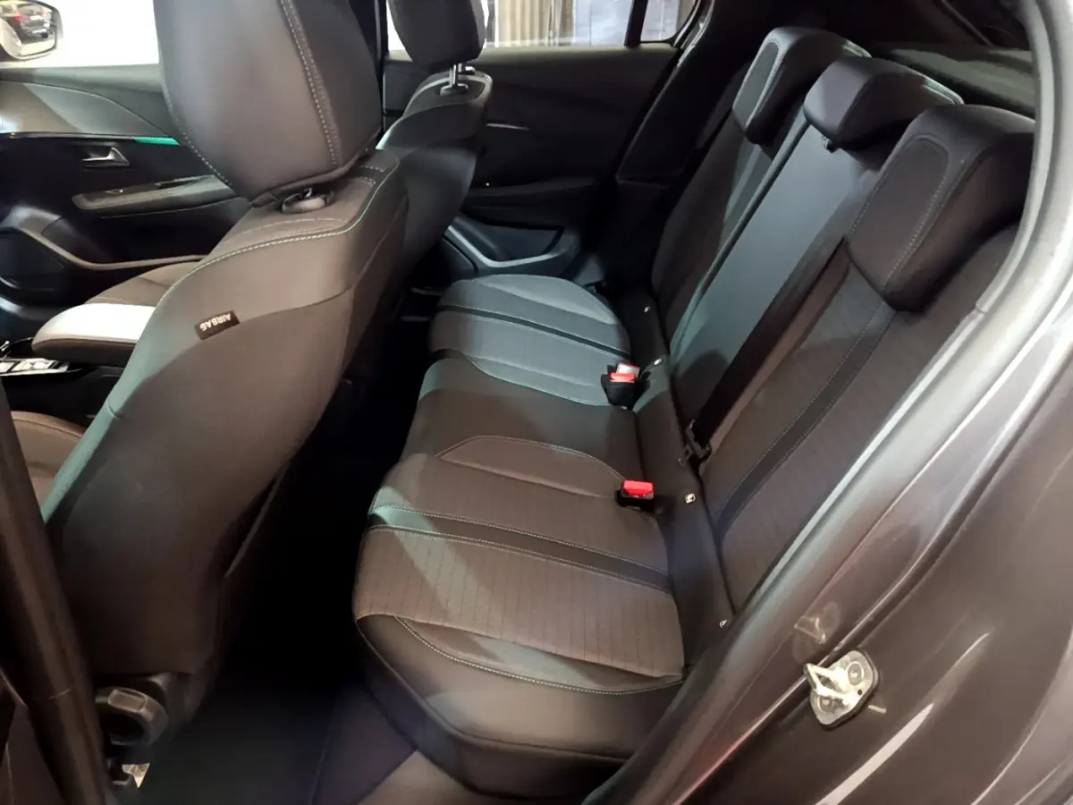 Vue intérieure côté droit sur la banquette arrière noire de la Peugeot 208 gris foncé avec appuie-têtes et ceintures visibles.